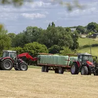Tracteur Massey Ferguson MF 5S Dyna-VT équipé d'un chargeur frontal chargeant avec des balles rondes d'enrubannage u
