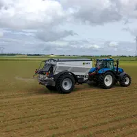 Epandeur d'engrais traîné Sky Agriculture Falcon T derrière un tracteur New Holland