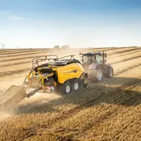 Presse à balles cubiques New Holland BigBaler1270 Plus Density derrière un tracteur New Holland