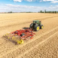 Déchaumeur à dents scalpeur Plano VT 6060 de Pöttinger derrière un tracteur John Deere.