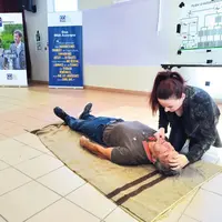 Une femme montre comment positionner la tête d'une personne inconsciente sur le sol, pour lui faire du bouche à bouche.