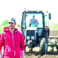 Jeune agriculteur dans un champ devant un tracteur