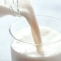 Du lait en train d'être versé dans un verre.