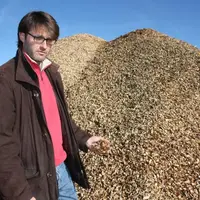 Kévin Chile devant les plaquettes stockées à l’extérieur en vue de leur séchage. Par la suite, le tas sera recouvert d’une bâche.