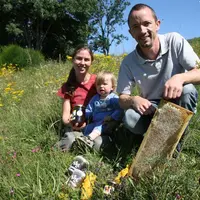 Emmanuel et Véronique avec l'un de leur deux fils sur une parcelle de prairie fleurie.
