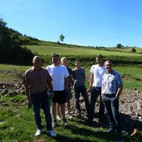 Les responsables syndicaux avec les associés du Gaec de la Narce sur une parcelle sur laquelle un torrent a laissé une large traînée de gravats.