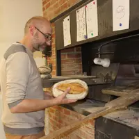 Le boulanger face au “Voisin”, son four à bois. Avant cuisson, les pains sont striés de façon à évacuer leurs gaz.