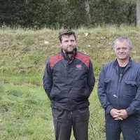 Quentin et André Sergent devant la digue de 2,5 m de haut qui encercle désormais le point bas de l’élevage et de la méthanisation.
