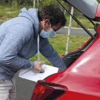 Les producteurs, qui ont préparé les commandes à l'avance, emplissent les coffres des clients de colis de produits locaux.