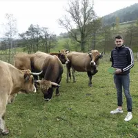 Adrien Combes exhibe fièrement la plaque de vainqueur du concours, auprès de ses vaches Aubrac, dans la prairie des Bastides.