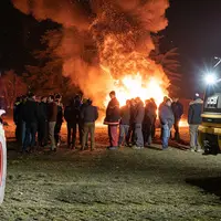 Un groupe de gens dehors devant un feu dans la nuit.