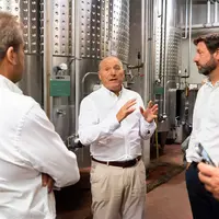 Un homme parle à un groupe devant des cuves de vin.