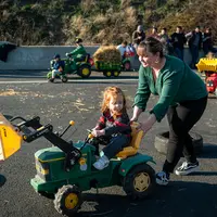 Une mère pousse sa fille, assise sur un tracteur à pédales.