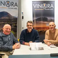 Trois hommes assis devant des kakémonos Vinora.