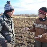 Un homme et une femme discute sur une parcelle de terre.