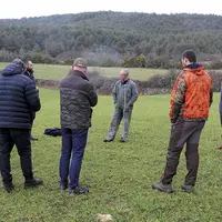 Un groupe d'hommes discute en rond au milieu d'une parcelle agricole.