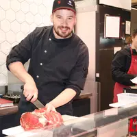 Boucher découpe de la viande sur l'étal du rayon traditionnel.