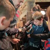jeunes enfants caressent un veau tenu par son éleveur