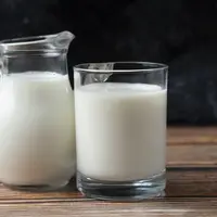carafe de lait et verre de lait sur une table fond noir