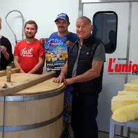 Quatre hommes dans une fromagerie autour d'une gerle en bois, typique du Cantal.