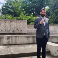 Un homme tenant une photo devant un monument aux morts