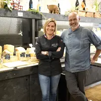 Un homme et une femme posent devant un rayon de fromages