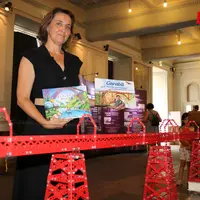 Femme tenant deux livres pour enfants devant la maquette du viaduc du Garabit