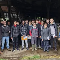 Un groupe de lycéens à l'entrée d'un bâtiment d'élevage