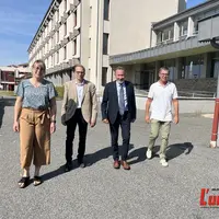 Quatre personnes, une femme et trois hommes marchant de face devant un lycée