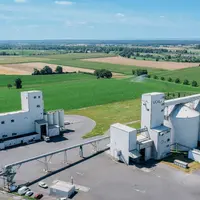 Vue aérienne de l'usine de trituration, comprenant des bâtiments et des silos au milieu de champs