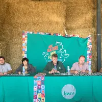 des gens assis devant une table, des bottes de paille derrière eux