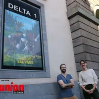 deux personnes devant un mur et une affiche de cinéma