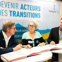 Deux hommes et une femmes assis à des table, des documents à signer devant eux