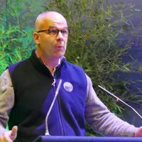 Arnaud Rousseau parle à la tribune devant un pupitre et des micros