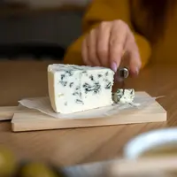 femme coupant un fromage bleu avec un couteau