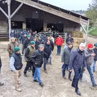 Un groupe d'homme marchant devant un bâtiment d'élevage sous la neige