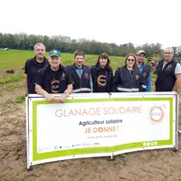 Un groupe se tenant derrière une banderolle "glanage solidaire" au milieu d'un champ