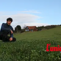 Un homme accroupi au milieu de l'herbe.
