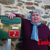 Une dame pose la main sur une boite aux lettres ou figure un numéro d'adressage, le 2.