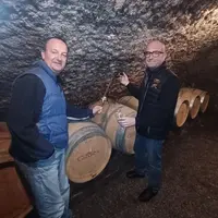 Deux vignerons dans une cave devant des tonneaux de vin