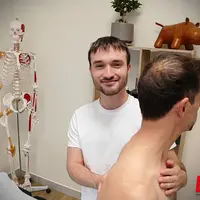 Un ostéopathe appose les mains sur le torse et le dos d'un patient.