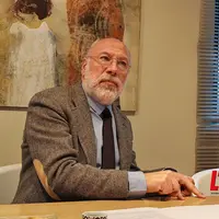 Sénateur Sautarel assis derrière son bureau, pointe du doigt le dessus de la table.