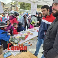 A droite deux hommes et à gauche des enfants avec des casques mangent du fromage