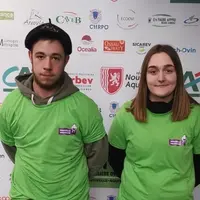 un jeune homme et une jeune fille devant un panneau de logos