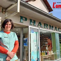 Une pharmacienne, devant sa pharmacie.