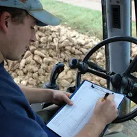 jeune salarié d'EDT au volant d'un engin agricole remplit un formulaire.