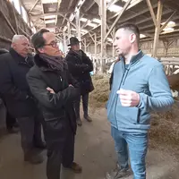 2 hommes discutent dans un bâtiment agricole, un troisième écoute