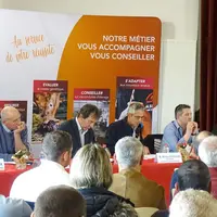 5 hommes assis derrière une table, face à une assemblée