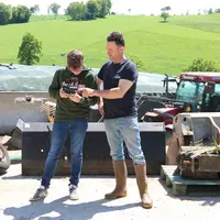Deux hommes devant un silo de ferme faisant décoller un drone