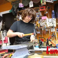 Sellière bourrelière au travail, martele les rivets d'un licol de cuir